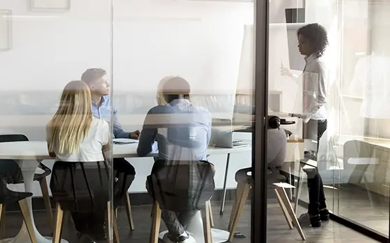office workers having a meeting in a meeting room looking at a flipchart office workers having a meeting in a meeting room looking at a flipchart