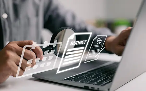 someone looking a laptop and a hologram of an icon representing a budget